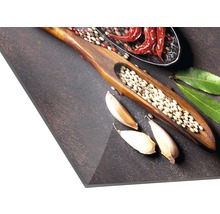 Specerijen zoals chilipepers, knoflook, laurierblaadjes en peper op een donkere achtergrond.
