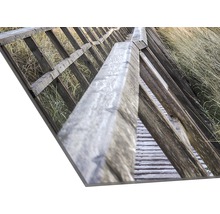 Fotoafdruk van een houten steiger met een leuning in het gras