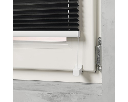 Close-up van een zwart plisségordijn op een raam