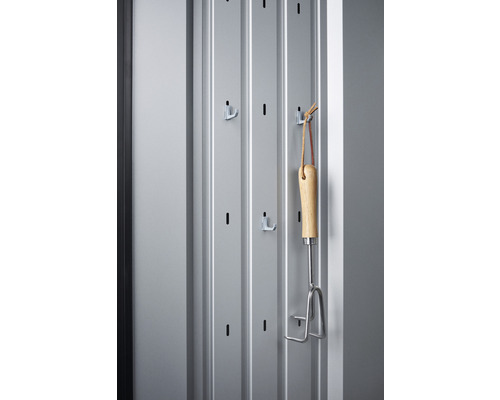 Gereedschapshouder met tuingereedschap aan een grijze muur