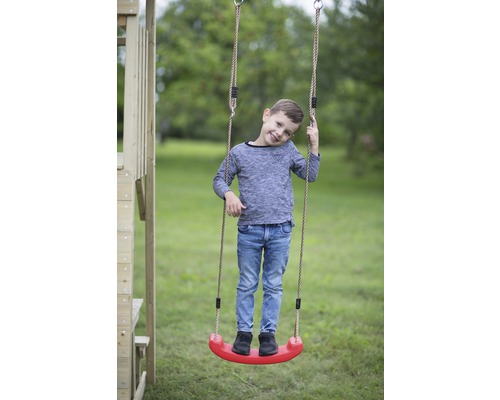 Jongen staat op een kinderschommel met touwen in de tuin.