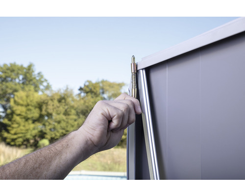Gedetailleerd aanzicht van de montage van een tuinhuis met een hand die een metalen stang vasthoudt