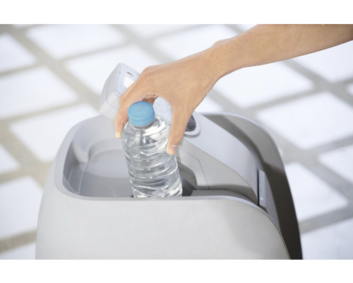 Een hand plaatst een waterfles in een vuilnisemmer.