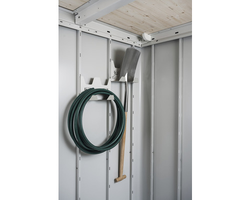 Interieur van een tuinhuis met tuinslang en spade aan de muurbeugel