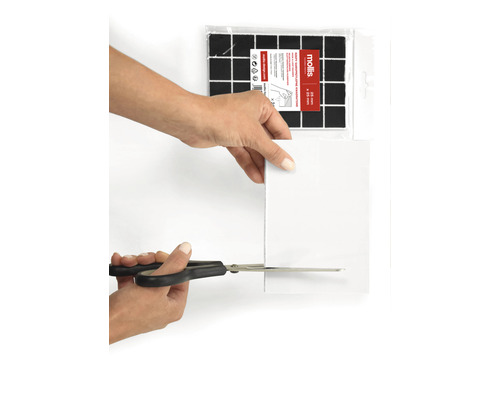 Een persoon knipt een viltglijder met een schaar. Viltglijders om op maat te knippen zijn op de achtergrond te zien.