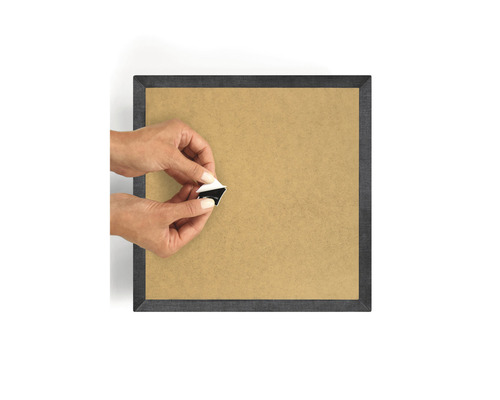 Persoon bevestigt een zelfklevende ophanging aan een fotolijst achterwand.