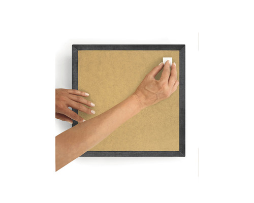 Persoon bevestigt een plakstrip op een fotolijst.