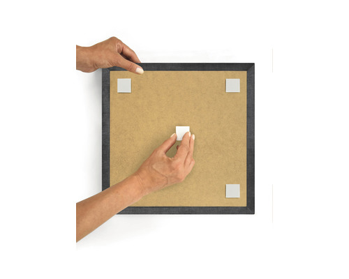 Persoon bevestigt zelfklevende pads aan een fotolijst