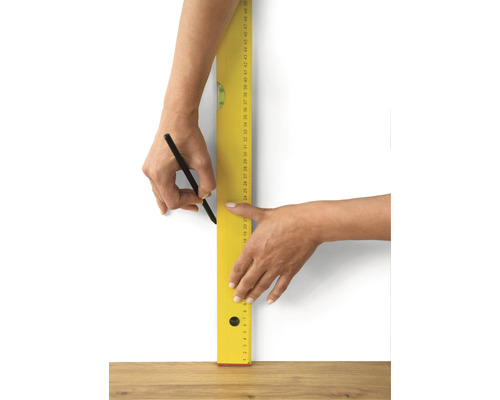 Persoon tekent een lijn met potlood en waterpas op een muur.