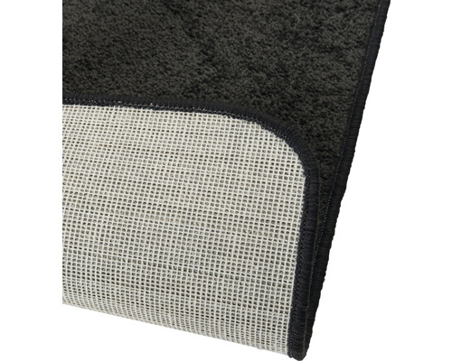 Detailweergave van een zwart badtapijt met antislip achterkant