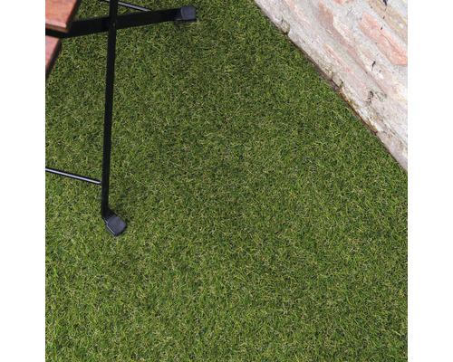 Close-up van kunstgras naast een stenen muur en een tafelbeen.