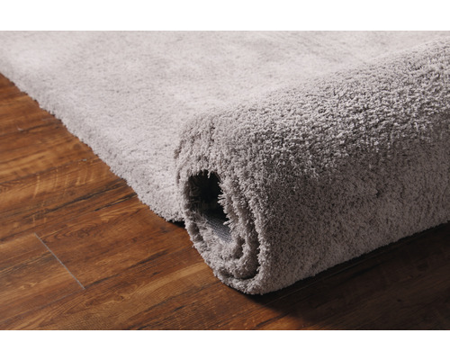 Grijze, opgerolde vloerkleed op houten vloer