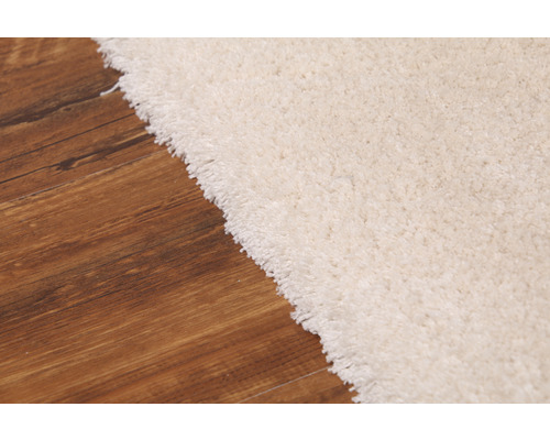 Detailweergave van een lichtgekleurd tapijt op een houten vloer