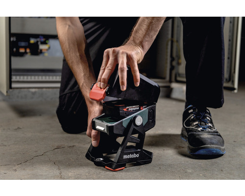 Iemand plaatst een batterij in een Metabo draadloze bouwlamp.