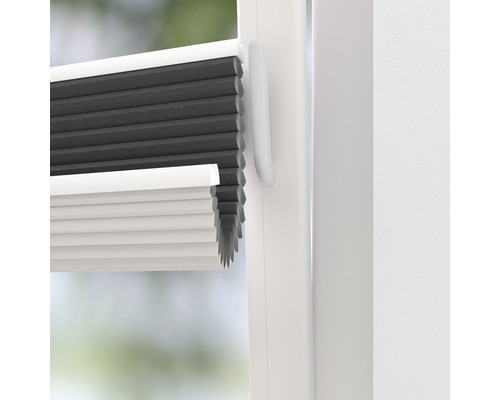 Close-up van een grijs en wit plisségordijn op het raam