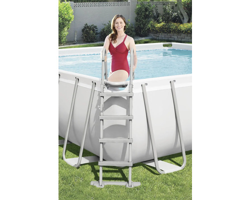 Vrouw beklimt een ladder in een rechthoekig zwembad in de tuin