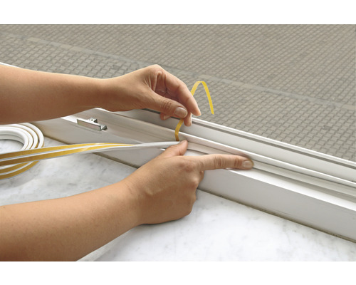 Een persoon brengt afdichtingstape aan op een raam.