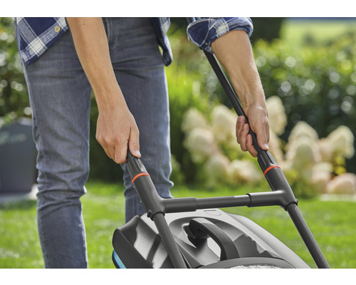 Een persoon bedient een gazonmaaier in de tuin.