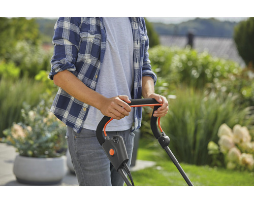 Een persoon bedient een gazonmaaier in de tuin.