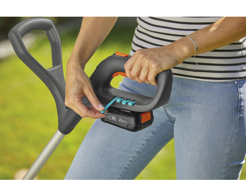 Een vrouw bedient een grastrimmer met accu