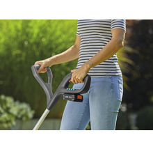 Vrouw bedient een accukantensnijder in de tuin.