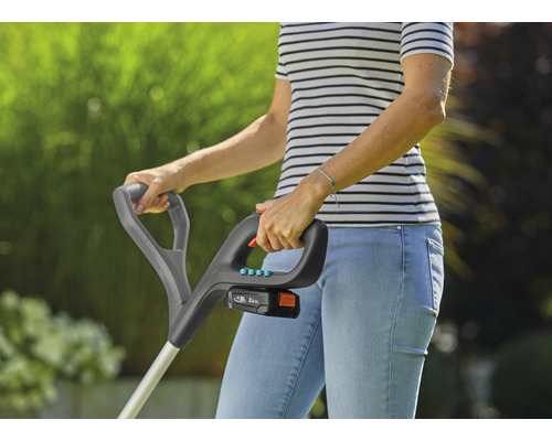 Vrouw bedient een accukantensnijder in de tuin.