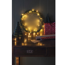 Gedecoreerde kerstscène met krans, lichtjes, cadeau en tafel
