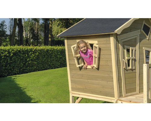 Kind speelt in een houten speelhuis met raam in de tuin.