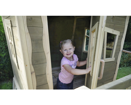 Meisje in houten speelhuis in de tuin