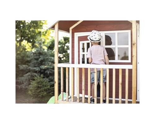 Een kind staat op de veranda van een houten speelhuis