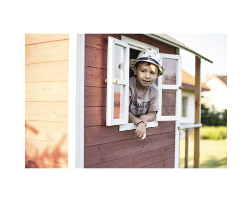 Een kind kijkt uit het raam van een speelhuis