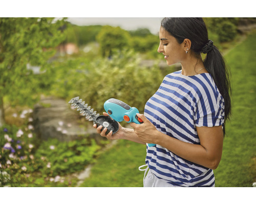 Vrouw houdt een Gardena accu grasschaar met verwisselbare messen in de hand.