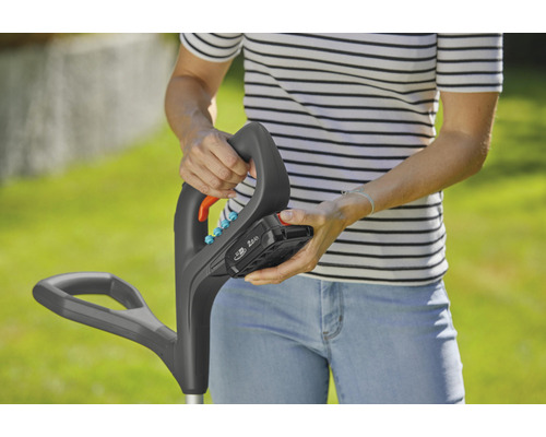 Een persoon bevestigt een accu aan een grastrimmer.