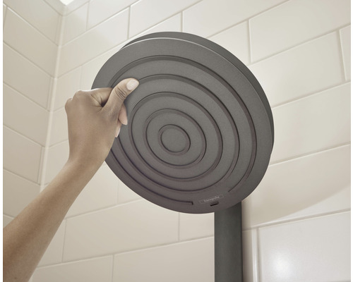 Hand raakt een ronde douchekop in de badkamer aan