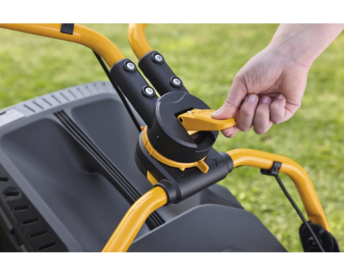 Detailopname van de bedieningselementen van een grasmaaier met een hand op de gele hendel