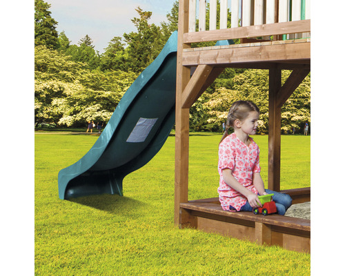 Speeltoren met glijbaan en spelend kind in zandbak