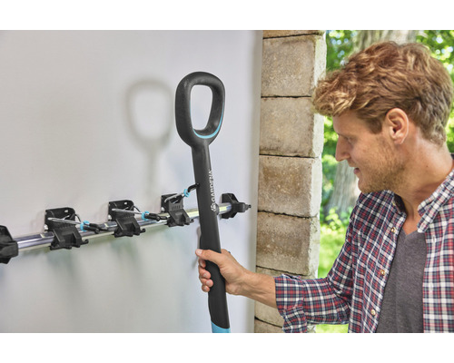 Man hangt tuingereedschap in een gereedschapshouder