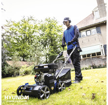 Een man maait gras met een Hyundai gazonbeluchter in een tuin.