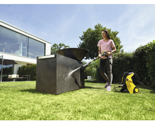 Vrouw reinigt buitensculptuur met hogedrukreiniger in de tuin.