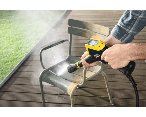 Een persoon reinigt een tuinstoel met een Kärcher hogedrukreiniger.