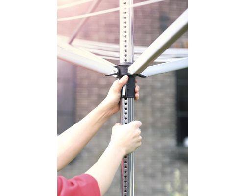 Persoon bedient een metalen waslijn in de tuin