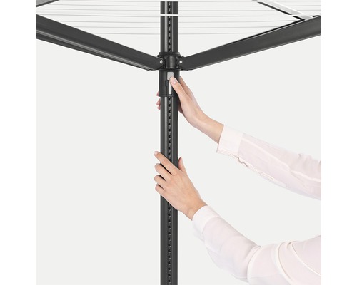 Detailopname van een wasmolen met een persoon die de hoogte van de molen aanpast.