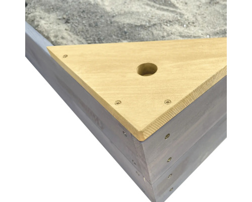 Detailopname van een driehoekige zandbak van hout met een boring