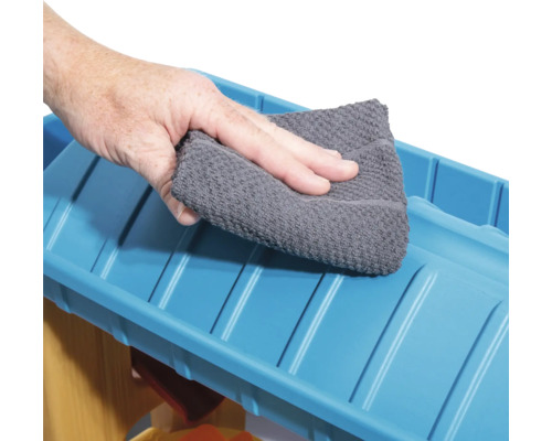Een hand veegt een blauw oppervlak schoon met een doek.