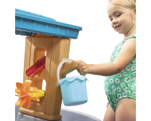 Meisje speelt met een waterspeeltafel in de tuin