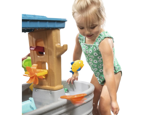 Meisje speelt met een waterspeeltafel in de tuin