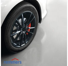 Detailopname van een auto met velg op een garagevloer met Remmers-logo