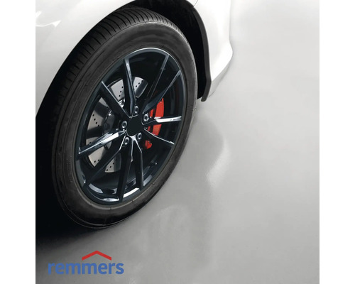 Detailopname van een auto met velg op een garagevloer met Remmers-logo