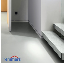 Lichte ruimte met betonnen vloer en trap met glazen balustrade. Remmers logo.