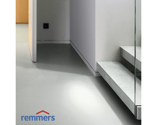 Lichte ruimte met betonnen vloer en trap met glazen balustrade. Remmers logo.